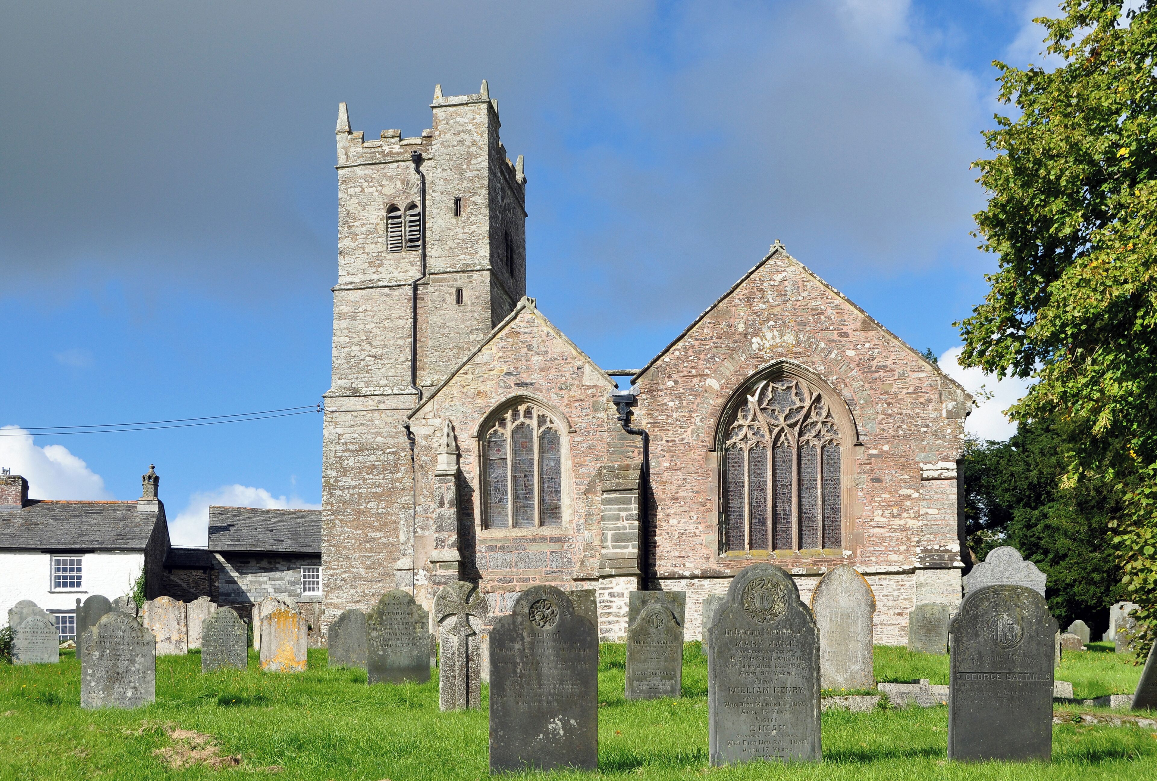 A historic church with a tall tower and arched windows, surrounded by a cemetery with headstones.