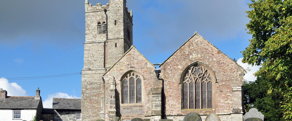A historic church with a tall tower and arched windows, surrounded by a cemetery with headstones.