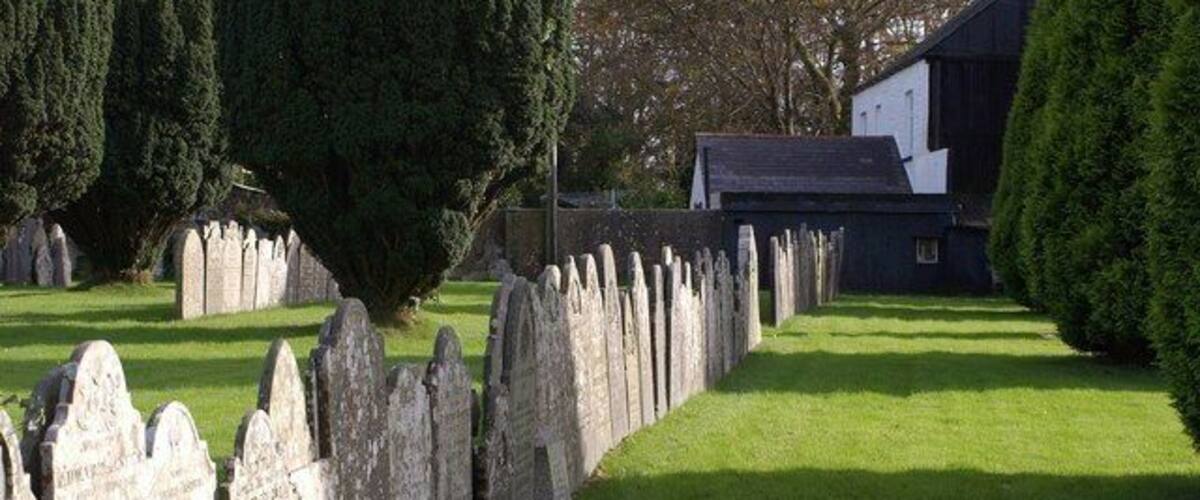 A cemetery with headstones and a building in the background.