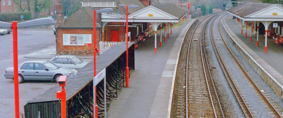 A railway station with multiple tracks, a platform, and a small brick building.