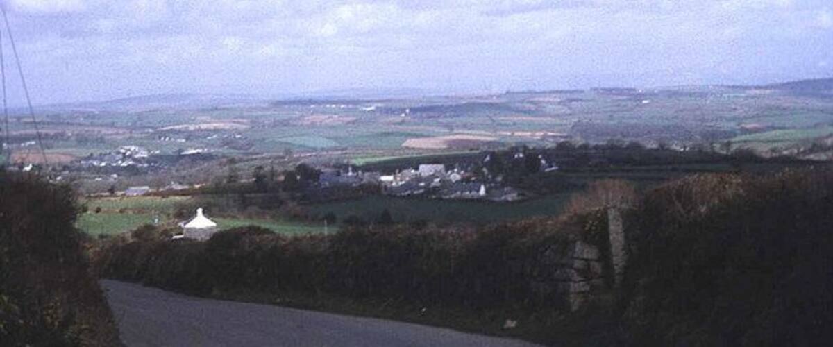 A rural landscape with a winding road, fields, and a white building in the distance.