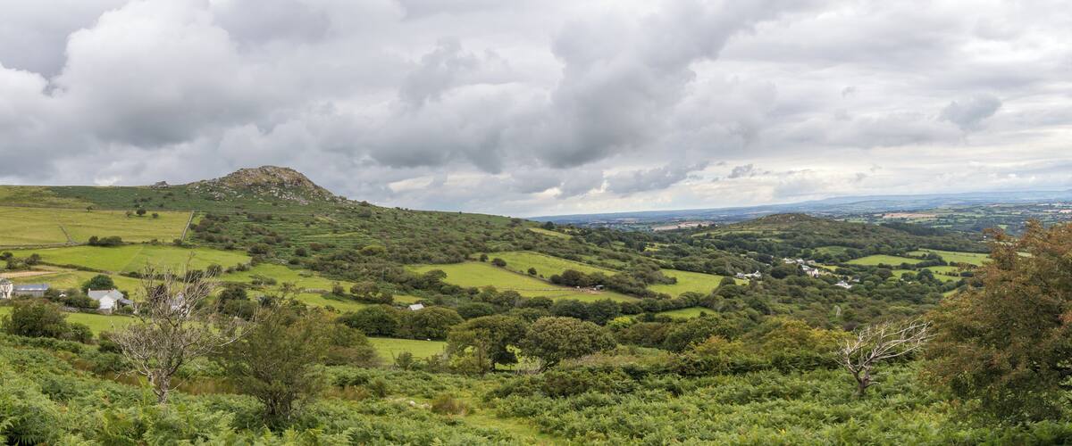 Rolling hills, a prominent hilltop, and scattered houses in a lush green landscape.