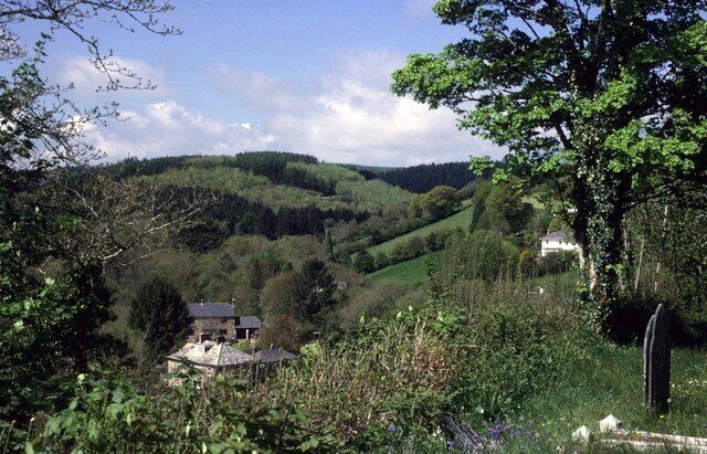 A rural landscape with rolling hills, a house, and a cemetery.