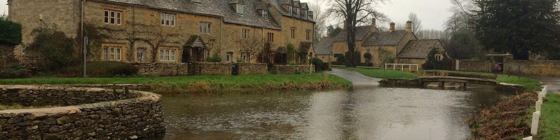 A stone bridge over a calm river, surrounded by traditional stone houses with sloped roofs.