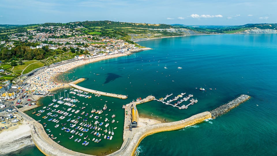 A coastal town with a marina, boats, and a beach.