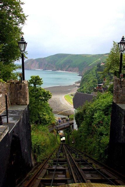 A railway track leading to a coastal area with a view of the sea and cliffs.