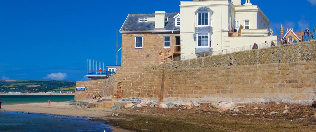 A coastal stone building with a balcony overlooking the beach.