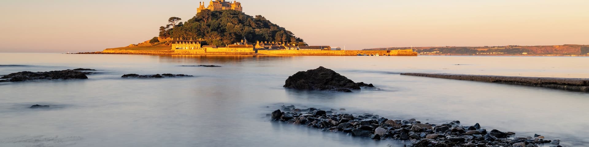 A castle on a hill overlooking calm waters.