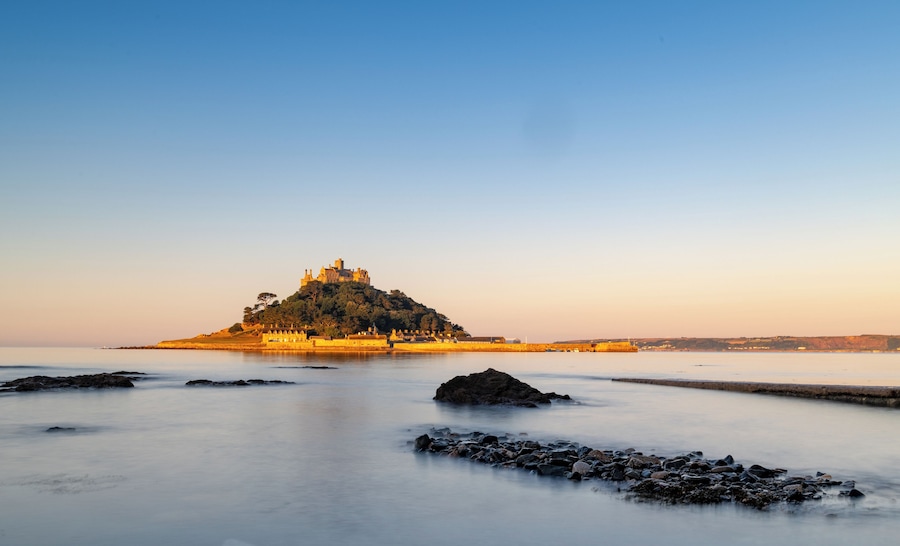 A castle on a hill overlooking calm waters.