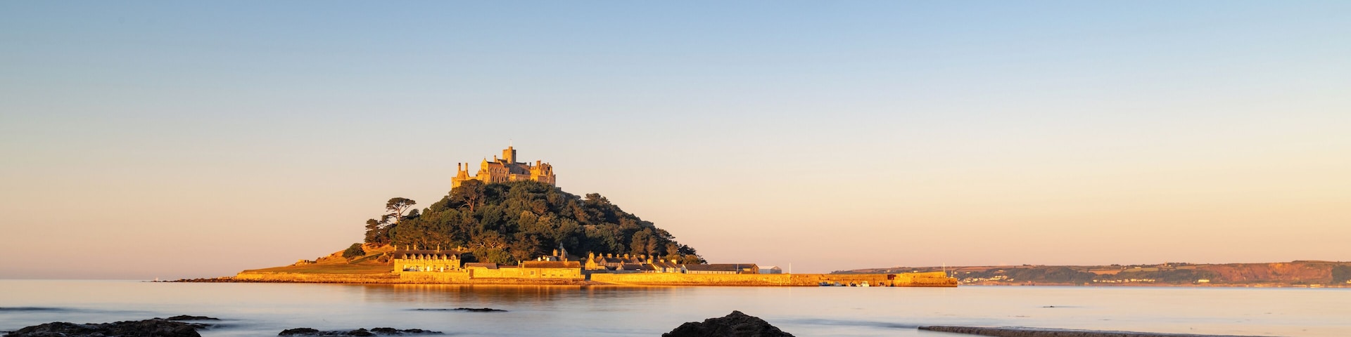 Um castelo numa colina com vista para águas calmas.