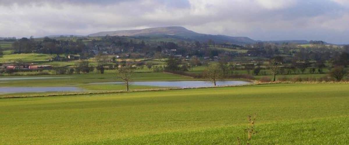 A rural landscape with rolling hills, a lake, and scattered houses.