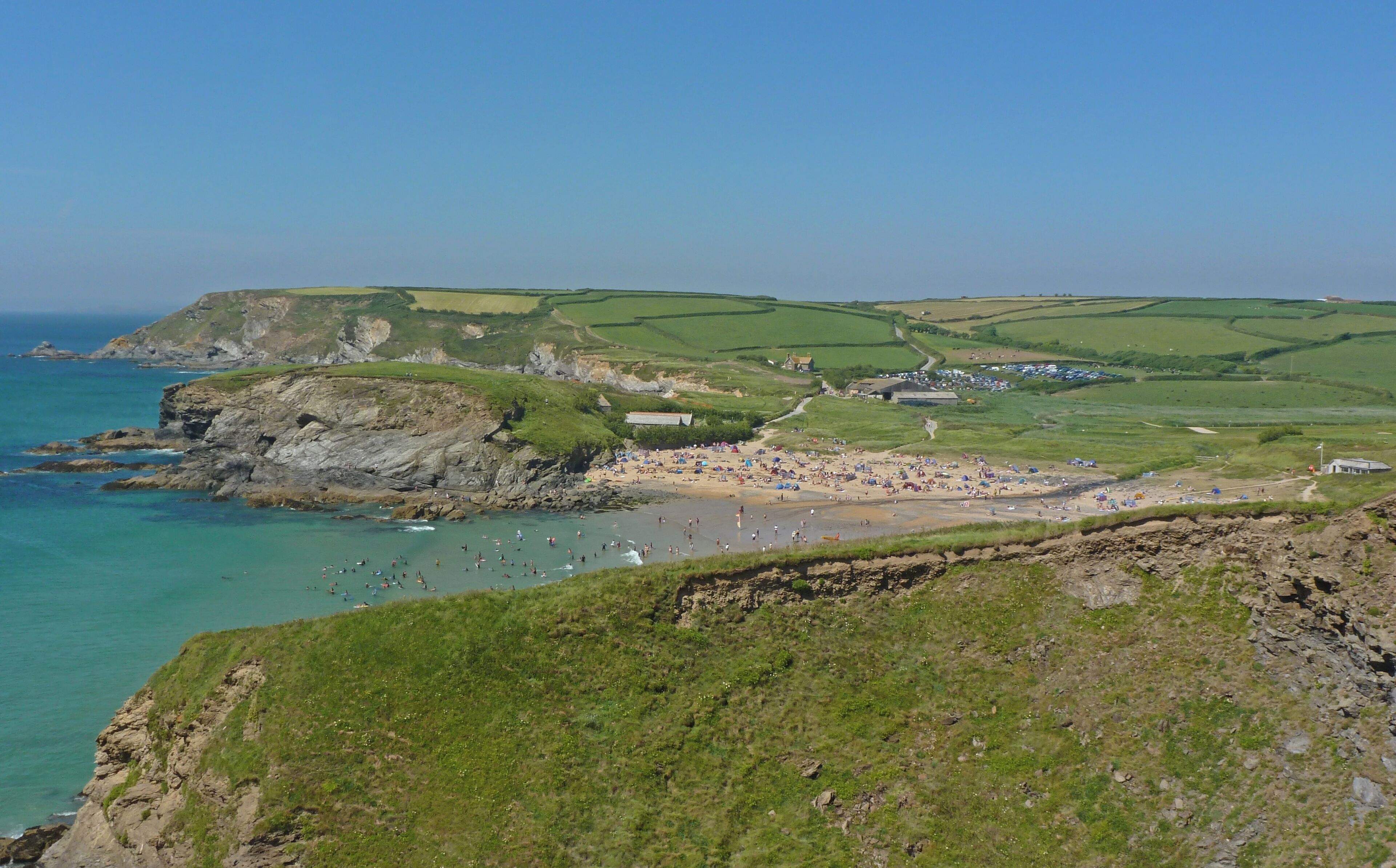 A coastal landscape with cliffs, a beach, and a village.