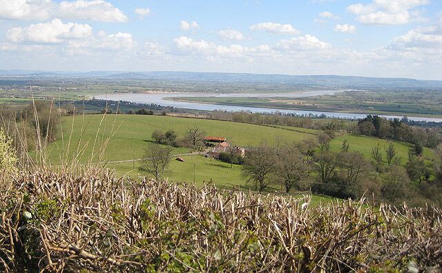 A river, green fields, and a distant building.