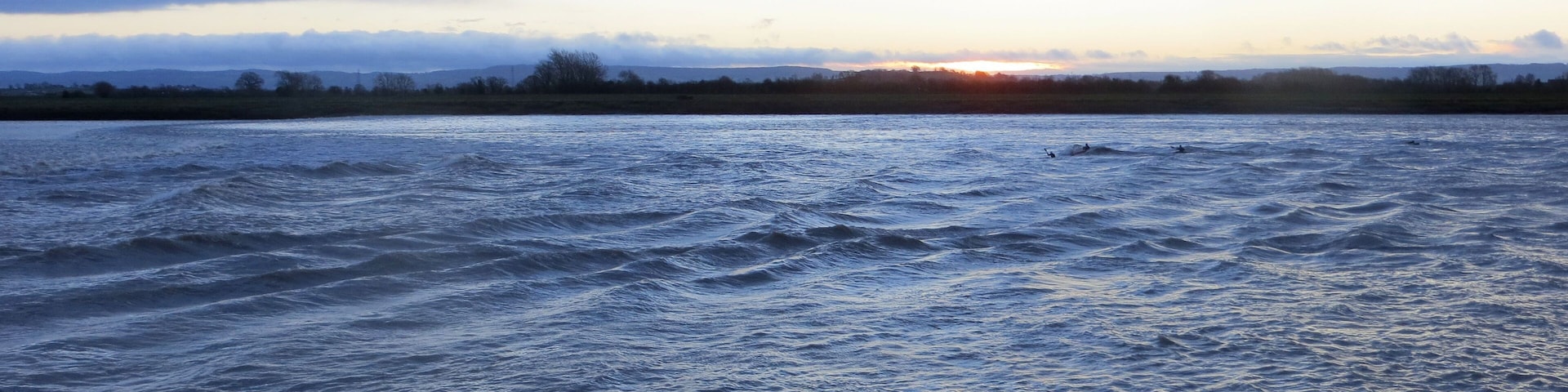 Una masa de agua con olas, cielo nublado y un horizonte lejano.