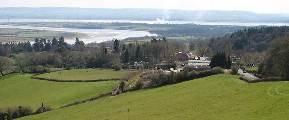 Grange Village from Dean Hill The road heads down to Newnham-on-Severn. The Severn makes it way round the great horseshoe bend and on to Bristol. Sand/mudbanks are exposed so it must be low tide.