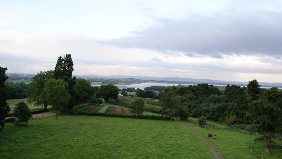 A lush green field with a distant lake and rolling hills.