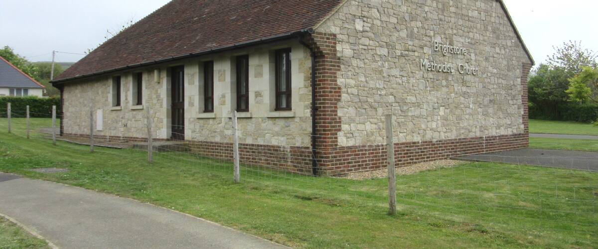 A stone Methodist Church with a brick base and a tiled roof.