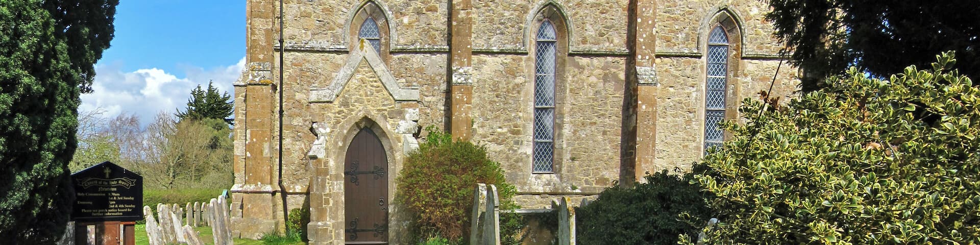 A stone church with a tiled roof, a central arched doorway, and a path leading to it.