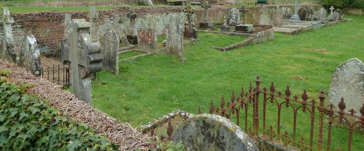 An old cemetery with stone headstones and a rusty iron fence.