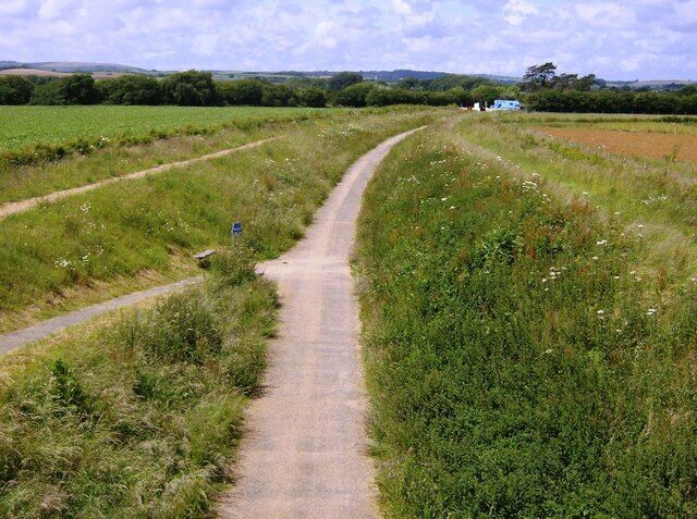 NCN 23, near to Merstone, Isle of Wight, Great Britain. Looking north-west towards Newport, this is the former Sandown to Newport railway line now used as a cycle trail. The minor road crossing here still uses the original bridge, whilst the crossing in the distance by the blue horsebox (Merstone Lane) is a former level crossing.