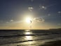 Atardecer sobre el océano con un kitesurfista y una costa distante.