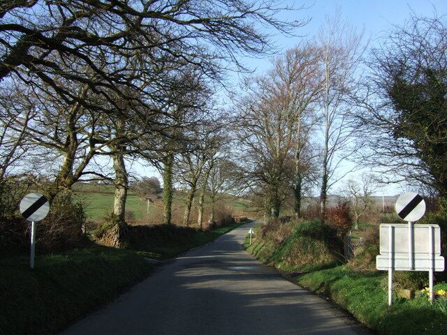 Lane to Voulsdon Cross Go as fast as you like. The delimiting signs at the north end of Bratton Clovelly, and a view down the treelined country lane north.