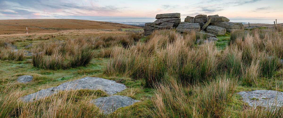A stone circle in a grassy field with a coastal view.