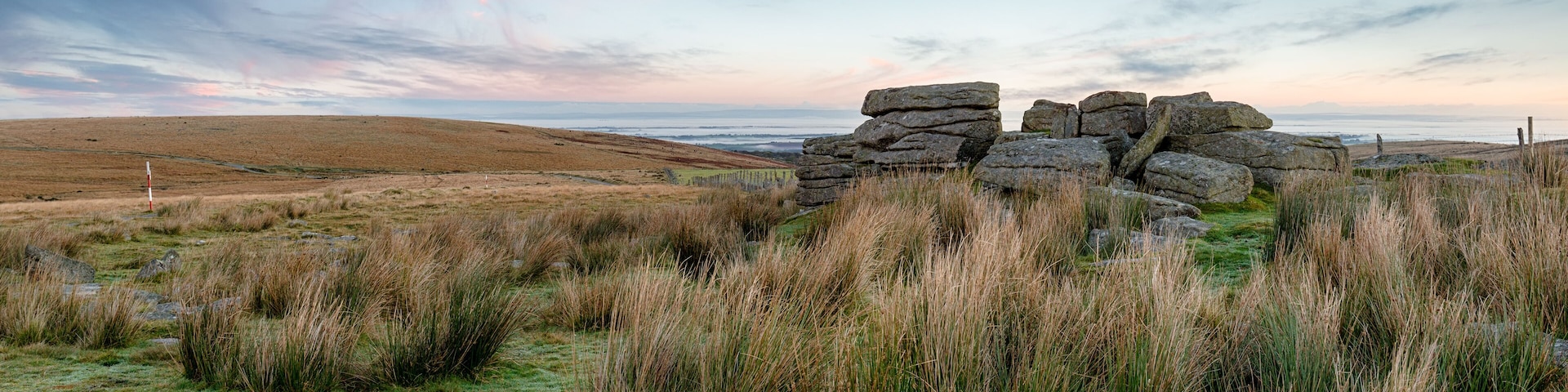 A stone circle in a grassy field with a coastal view.