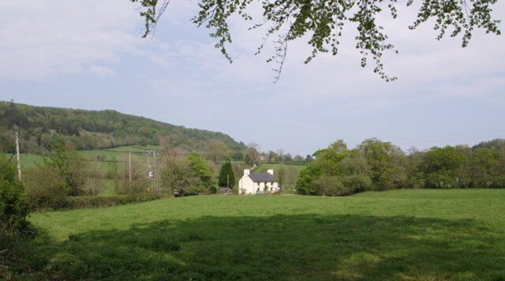 Ford Cottage A view from Lowertown, northeast of Coryton. On the left, above the fields, Lew Wood rises to Eastcott Beacon (the summit of the ridge is just out of square). Beyond the cottage, the lane climbs towards Eastcott.