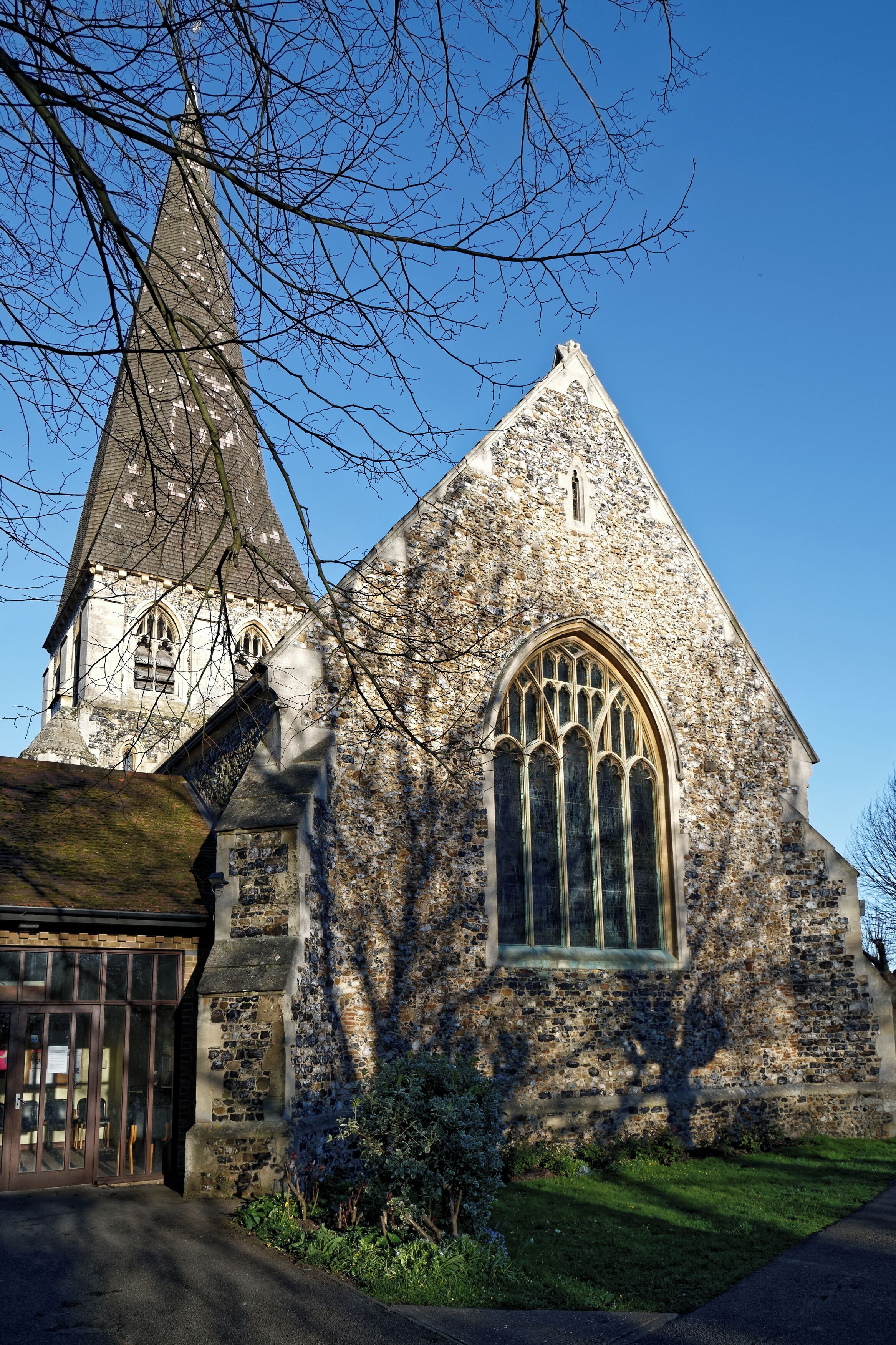 A stone church with a pointed steeple and a large arched window.