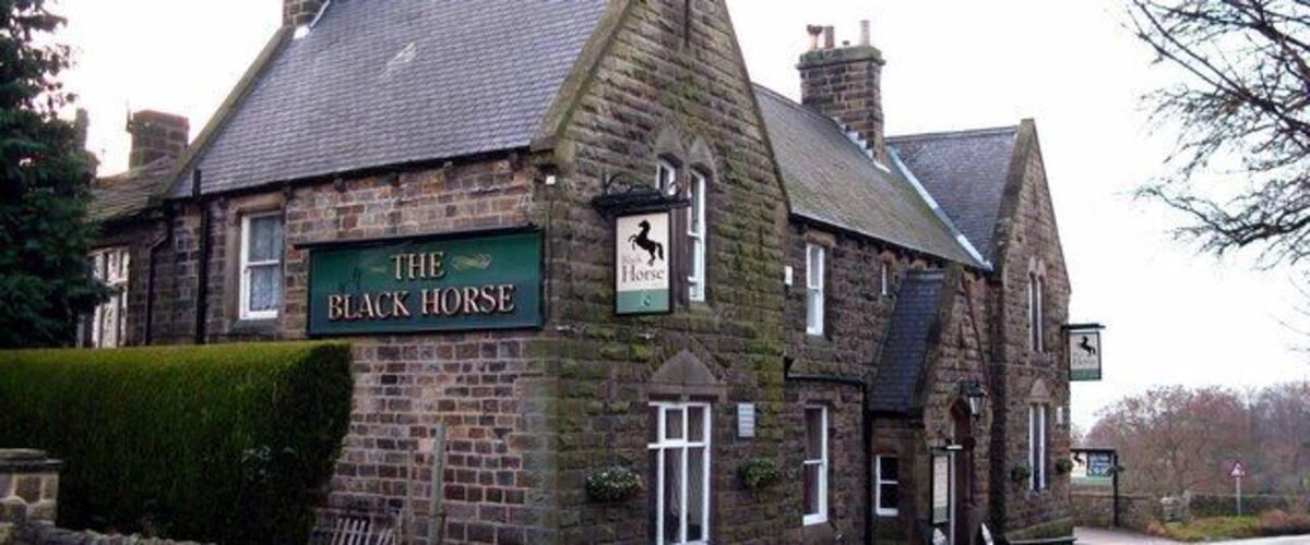 A traditional stone building with a sign reading "The Black Horse."