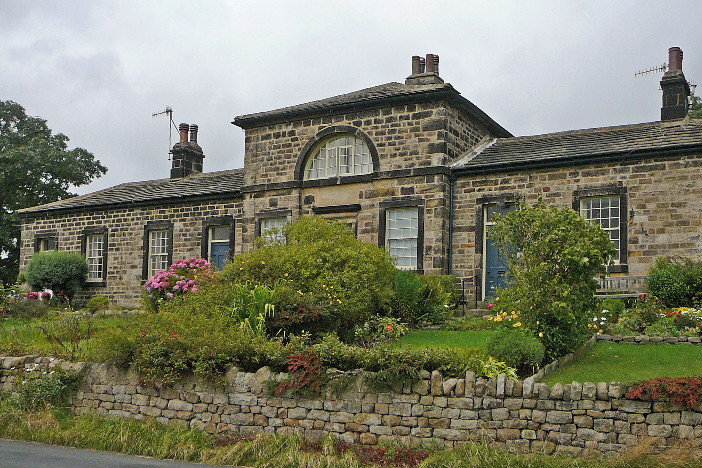 A stone building with a large arched window and multiple chimneys.