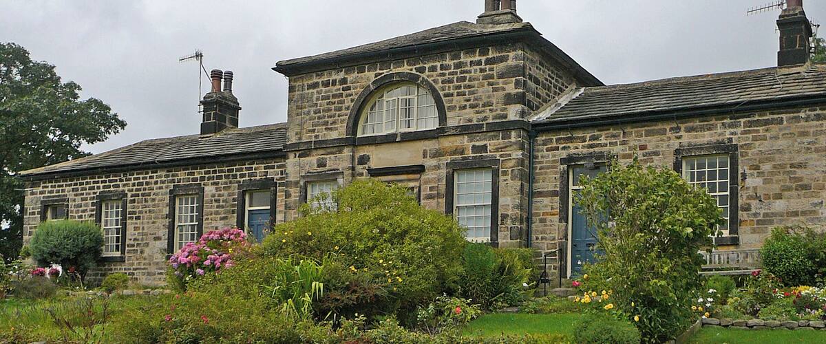A stone building with a large arched window and multiple chimneys.