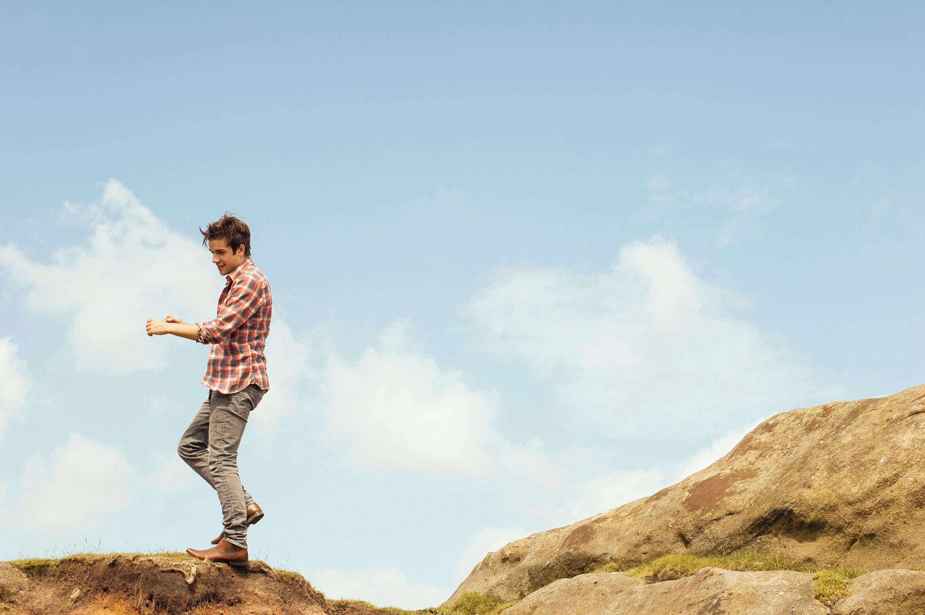 A person standing on a rock with a clear sky in the background.