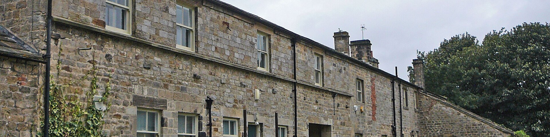 A stone building with multiple windows and a small garden area.