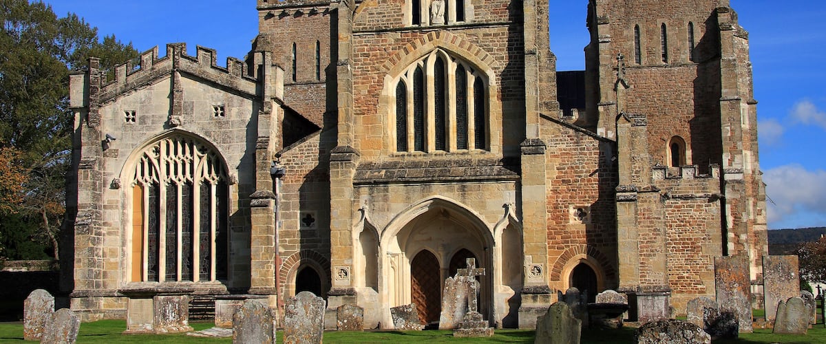 A historic church with a tall tower, arched windows, and a surrounding graveyard.