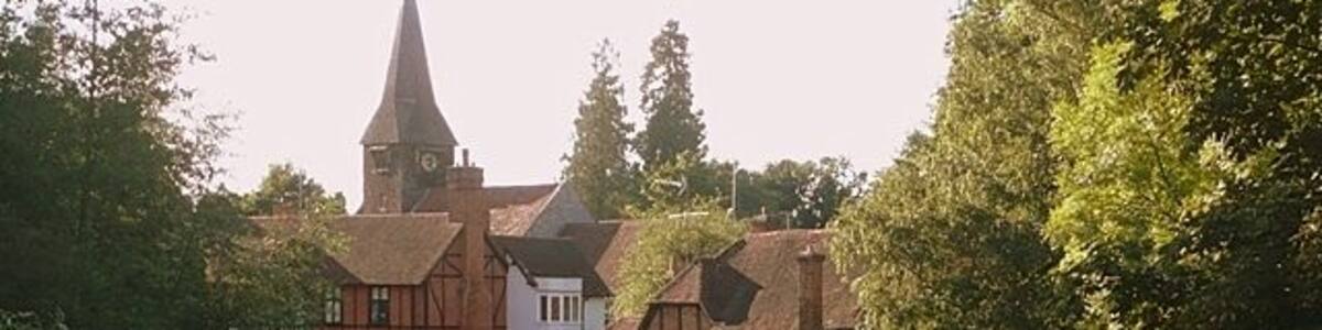 Whitchurch from the toll bridge St. Mary the Virgin church, Whitchurch, and its surrounding buildings around the mill stream on the north bank of the Thames.