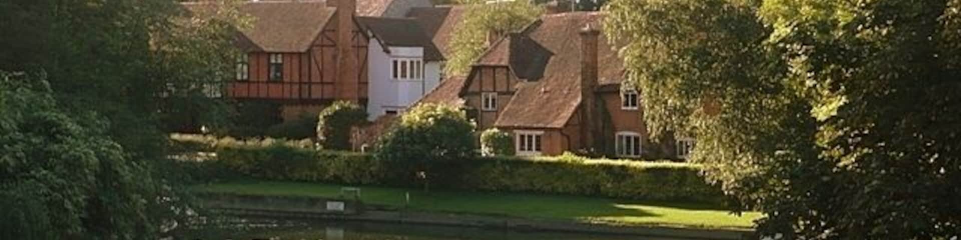 Whitchurch from the toll bridge St. Mary the Virgin church, Whitchurch, and its surrounding buildings around the mill stream on the north bank of the Thames.