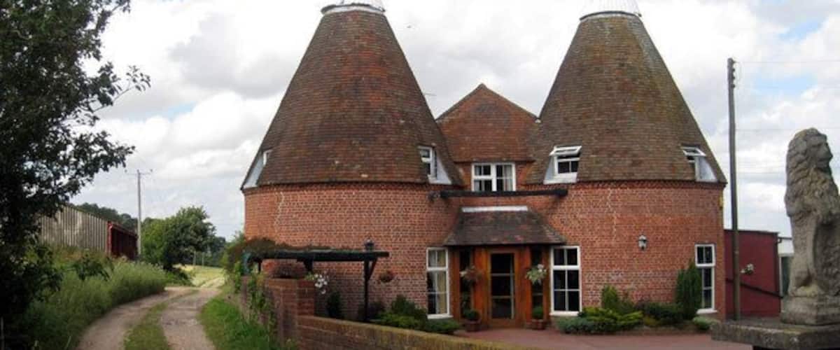 A brick building with two conical roofs, a pathway, and a stone lion statue.