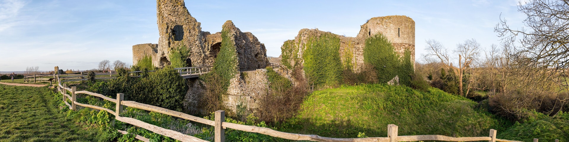 A historic stone castle ruin with ivy-covered walls and a wooden fence in the foreground.