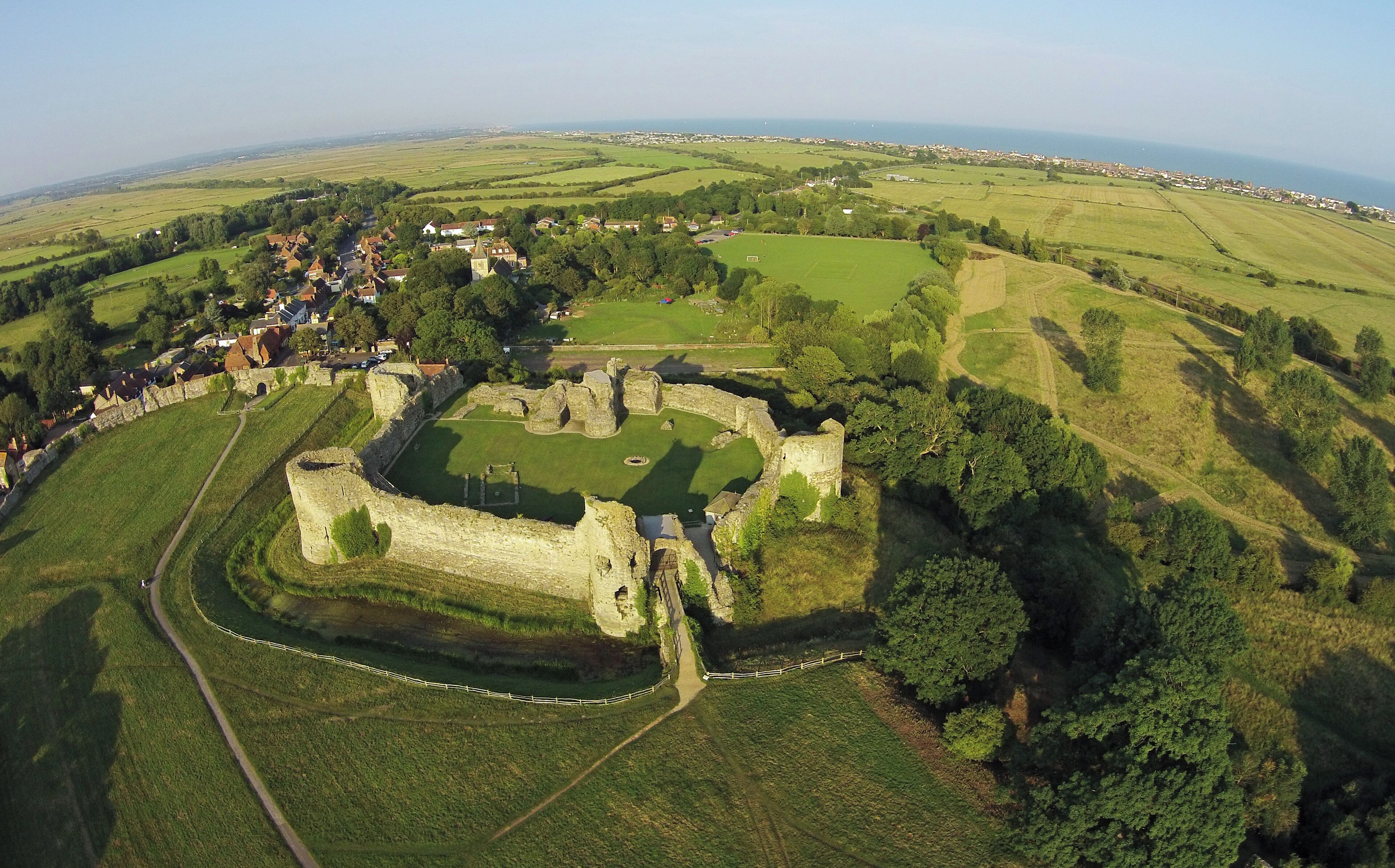 An aerial view of a historic castle surrounded by green fields and a small village.