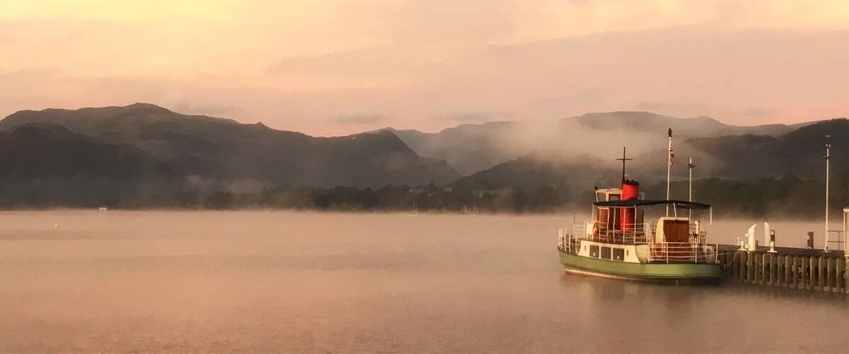 A boat docked at a pier with misty mountains in the background.