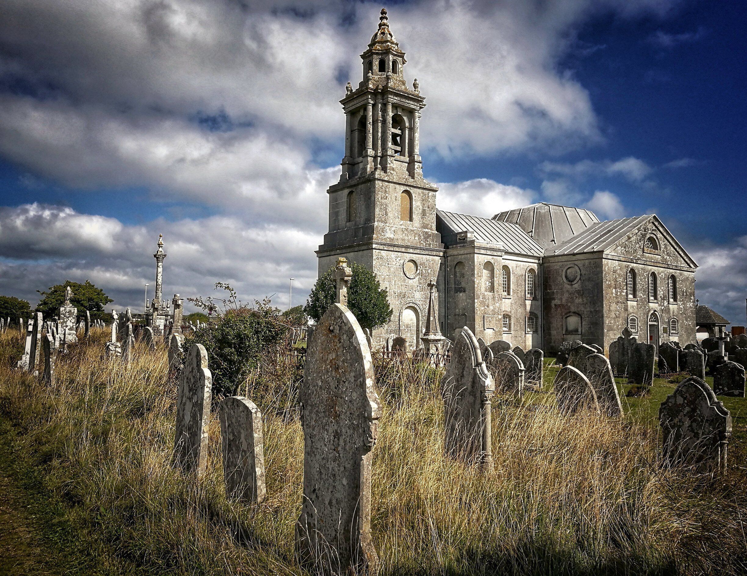 A historic church with a bell tower and a cemetery with headstones.