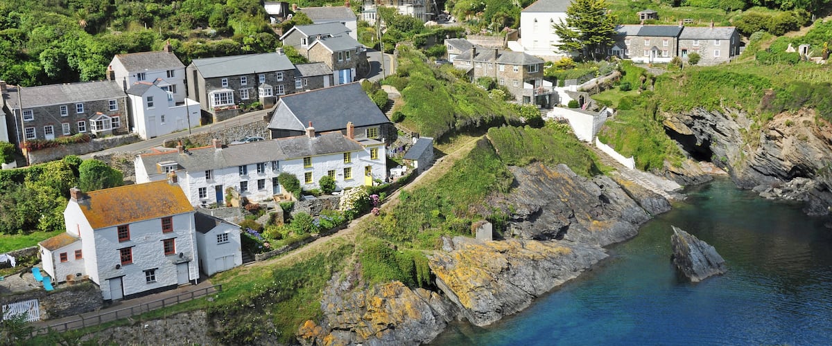 A coastal village with stone houses, a rocky shoreline, and a clear blue sea.