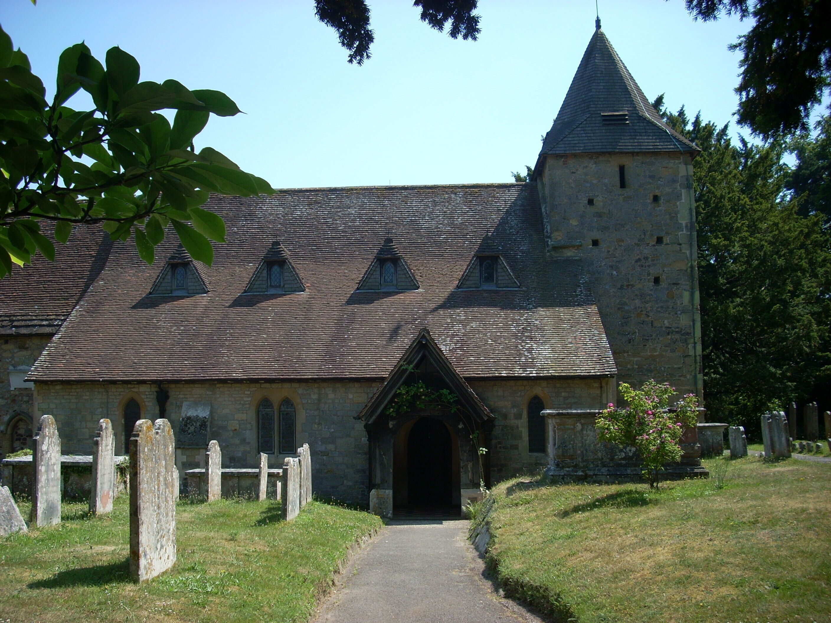 A stone church with a tower and a covered entrance.