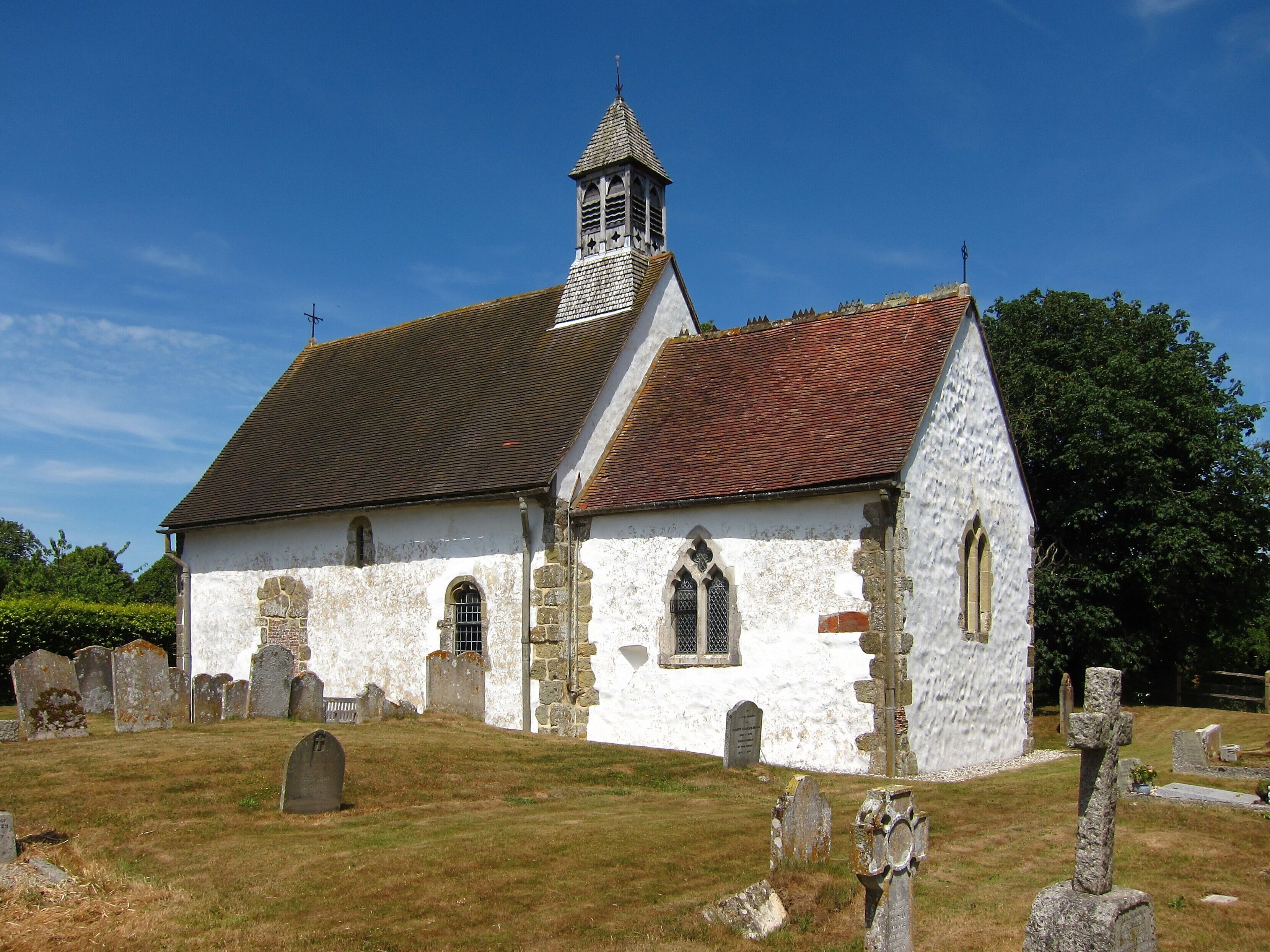A white church with a red-tiled roof and a bell tower.