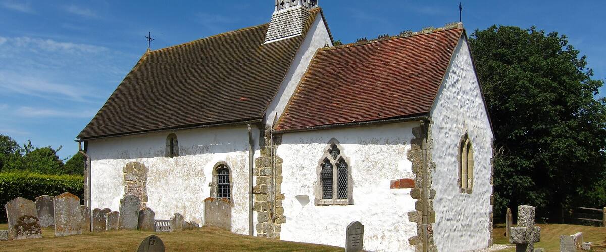 A white church with a red-tiled roof and a bell tower.