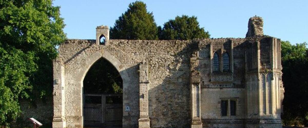 A stone archway leading into a ruined building with a bell tower.