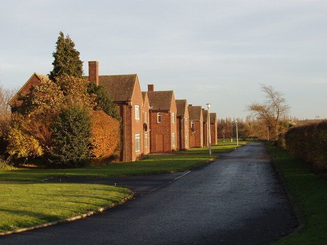 A residential street lined with brick houses, a curved road, and autumn foliage.