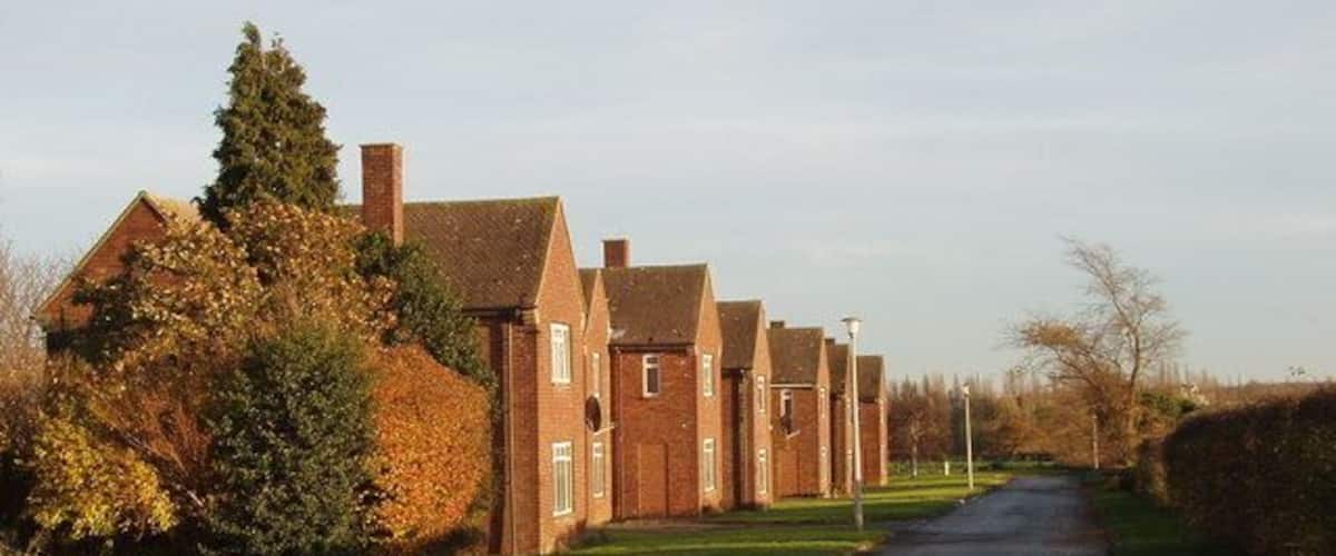A residential street lined with brick houses, a curved road, and autumn foliage.